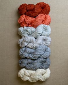 several skeins of yarn are stacked on top of each other in different colors