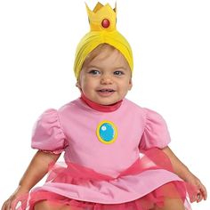 a baby wearing a pink princess costume sitting on top of a white floor with a yellow crown on it's head