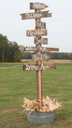 a wooden sign sitting on top of a grass covered field next to a metal bucket