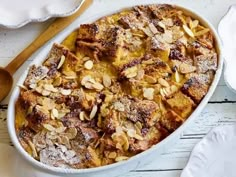 a casserole dish with almonds and powdered sugar in it on a white table