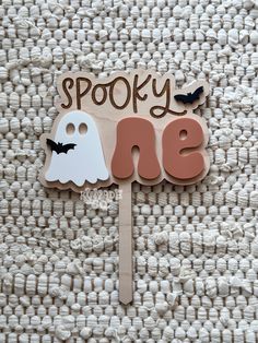 a wooden sign that says spooky one with two ghost faces on it and bats