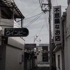 an alley way with signs on the buildings and telephone wires in the air above it