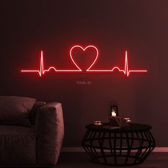 a living room with a couch, table and heart - shaped neon sign on the wall