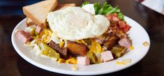 a white plate topped with hash browns and an egg on top of toasted bread