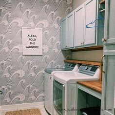 a washer and dryer in a laundry room next to a wall with a sign on it