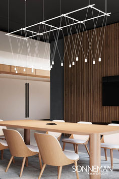 a large wooden table with white chairs and lights hanging from it's ceiling in a meeting room