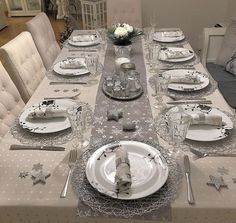 the table is set with silver and white plates, napkins, and place settings