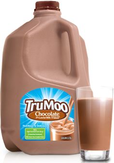 a jug of chocolate milk next to a glass with liquid in it and a bottle on the side