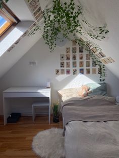 an attic bedroom with a bed, desk and plants on the wall above it's headboard