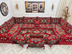 a large red couch covered in lots of colorful rugs