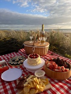 a picnic table with food and drinks on it, including strawberries, cheeses, crackers, and wine