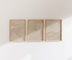 three wooden framed art pieces hanging on the wall