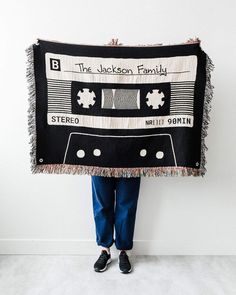 a person holding up a black and white blanket with an old fashioned cassette tape on it