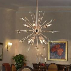 a chandelier hanging from the ceiling in a dining room with chairs around it