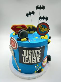 a blue cake with batman, wonder woman and justice league decorations on it's side