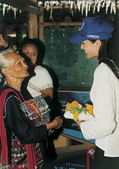 an old woman is handing flowers to another woman