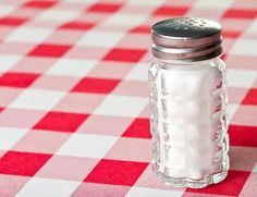 a salt shaker sitting on top of a red and white checkered table cloth