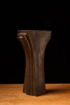 three metal vases sitting on top of a wooden table next to eachother