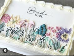 a wedding cake decorated with flowers and the words bride to be on it's side