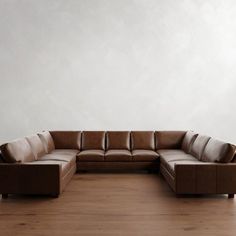 a brown leather couch sitting on top of a wooden floor next to a white wall