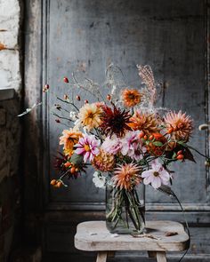 a vase filled with lots of flowers sitting on top of a wooden table