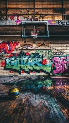 an old basketball court with graffiti on it and a basket ball in the foreground