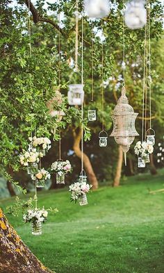 an outdoor wedding with hanging mason jars and floral centerpieces on the tree branches