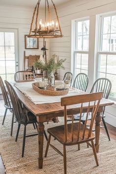 a dining room table with chairs and a basket on top of it in front of two windows