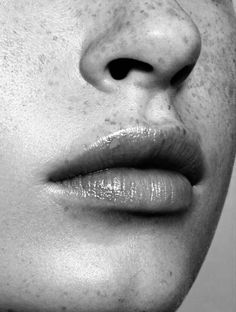 a woman's face with freckles on her lip and nose is shown in black and white