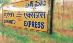 a yellow sign sitting on the side of a lush green field