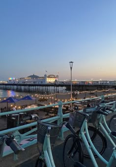 several bicycles parked next to each other in front of a pier with lights on it