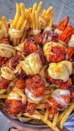 a bowl filled with pasta and meatballs covered in sauces, cheese and french fries