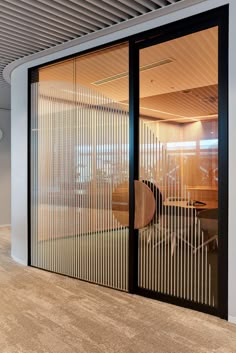 an office with sliding glass doors leading to the meeting room and desks in the background