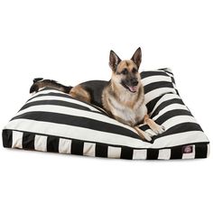 a dog laying on top of a black and white striped pillow with his tongue out