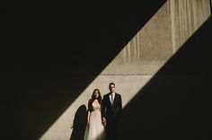 a man and woman standing next to each other in front of a wall with shadows on it