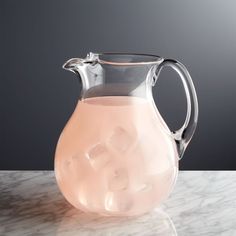 a glass pitcher filled with liquid sitting on top of a marble counter next to a black wall