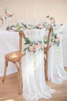 the chairs are covered with white drapes and floral sashes, along with candles