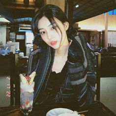 a woman sitting at a table with a drink in front of her and food on the plate