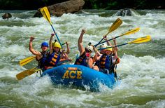 four people are rafting down a river with their arms in the air