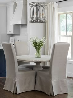 a dining room table with four chairs and a chandelier hanging from the ceiling