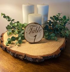 a wooden table with candles and greenery on it, next to a sign that says table 1