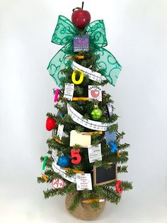 a small christmas tree decorated with ribbons and magnets for the number five on it