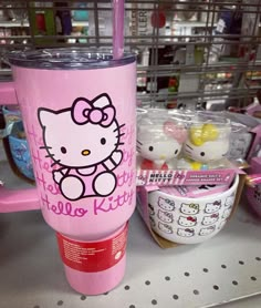 a pink hello kitty cup sitting on top of a table next to other items in a store