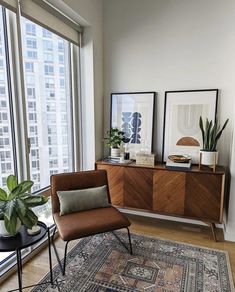 a living room with two chairs and a rug in front of large windows overlooking the city