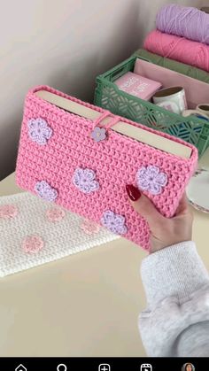 a woman holding a pink crocheted purse