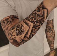 a man with lots of tattoos on his arm and shoulder holding up a playing card