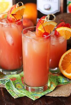 two glasses filled with orange juice and garnished with cherries