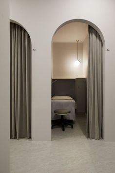 an arched doorway leads to a bedroom with a bed and desk in the corner, along with drapes on both sides