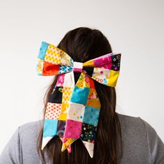 a woman with her back to the camera, wearing a colorful patchwork bow tie