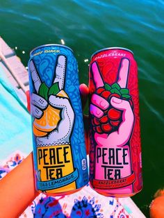 two cans of peace tea sitting next to each other in front of some water and oranges